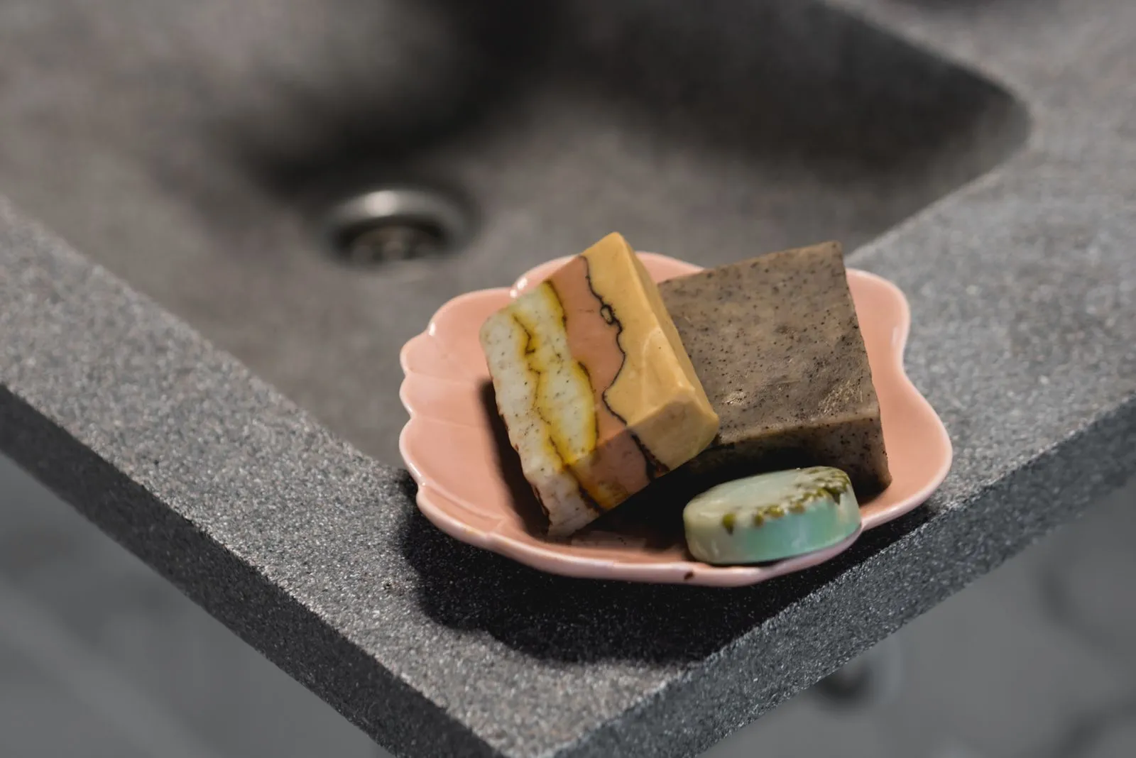 Close-up still life of handcrafted soaps on a pink tray, highlighting self-care and skincare essentials.